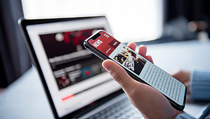 Smartphone and laptop show digital news content for company updates, press releases and publications.