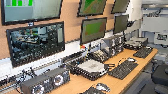Indoor spectrum control center with multiple monitors, hardware, and workstations.