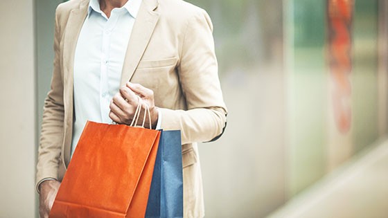Shopping experience in Roppenheim. A man holding colorful shopping bags in a modern retail environment.